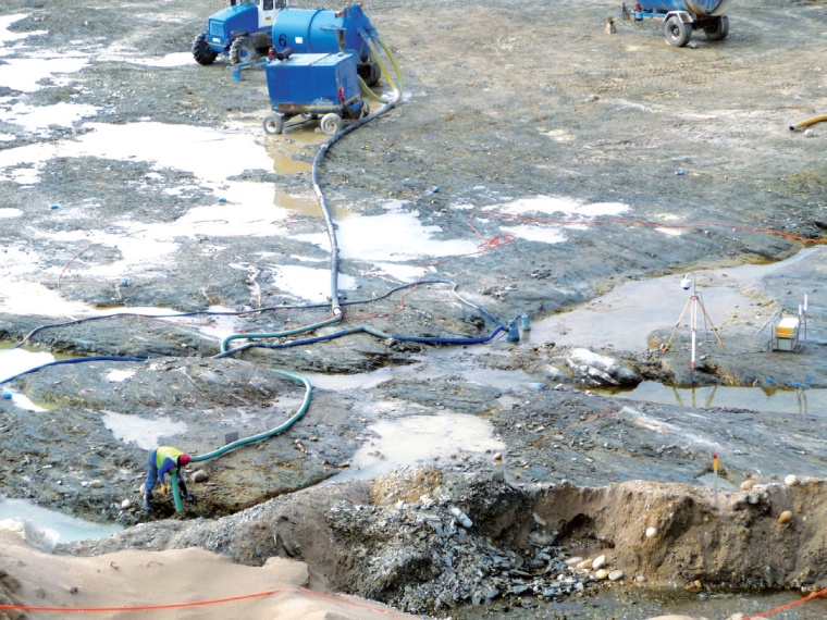 The bedrock is cleaned by workers using a containerized vacuum cleaning system....