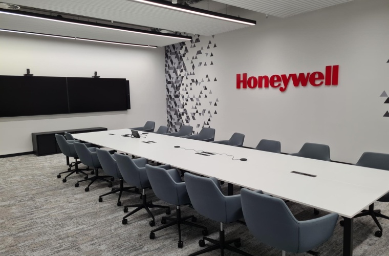 Ein großer moderner Konferenzraum mit einem breiten Konferenztisch, zwei Monitoren an der Rückwand und einem großen Honeywell-Logo an der Seitenwand
