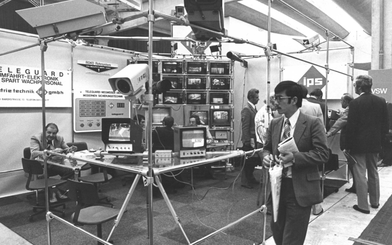 Messestand mit Überwachungs- und Sicherheitstechnik, mehreren Monitoren mit Kamerafeeds