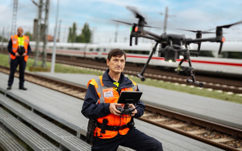 Mann mit Bediengerät vor fliegender Drohne