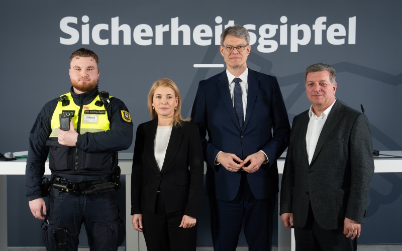 Drei Männer und eine Frau vor einem Hintergrund mit der Aufschrift „Sicherheitsgipfel“