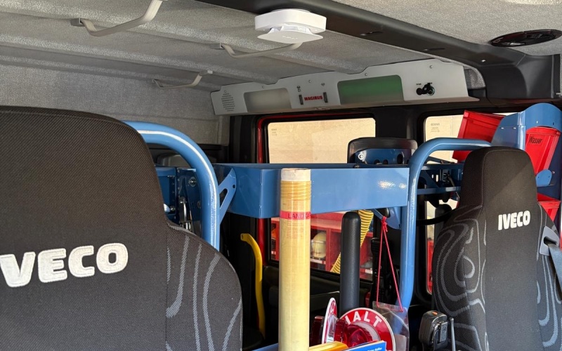 Innenraum eines Feuerwehrfahrzeugs mit Sitzen, Ausrüstung und montiertem Überwachungssensor an der Decke