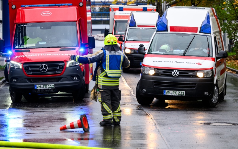 Einsatzkraft mit Schutzkleidung vor mehreren Einsatzfahrzeugen