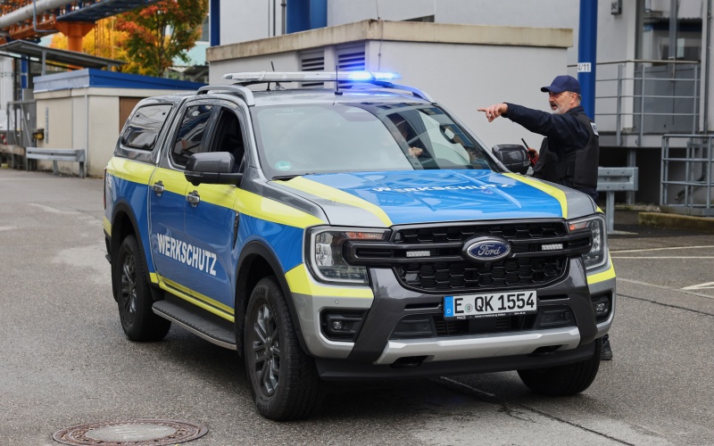 Mann neben Auto mit Aufschrift „Werkschutz“