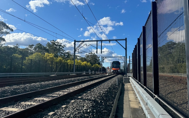Bahnschiene mit Zaunanlage und Lok im Hintergrund