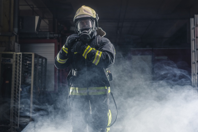 Portrait of a fireman wearing firefighter turnouts and helmet. Dark background...