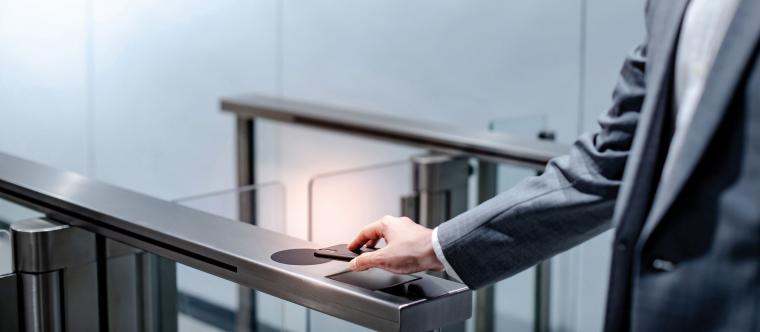 Ein Mann im Anzug legt sein Handy auf den Sensor eines Zutrittskontrollsystems