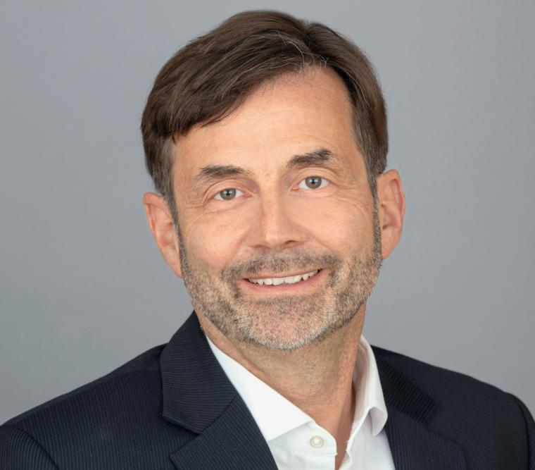 Profilbild eines Manns mit vollem Haar, grauem Bart, schwarzem Blazer und...