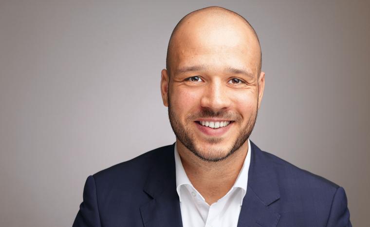 Profilbild von einem Mann mit gestutztem Bad, dunkelblauem Blazer und weißem...