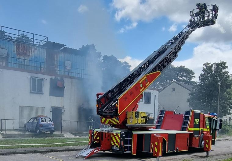 Ein Feuerwehrman steht vor einem rauchenden Übungshaus auf der ausgefahrenen...