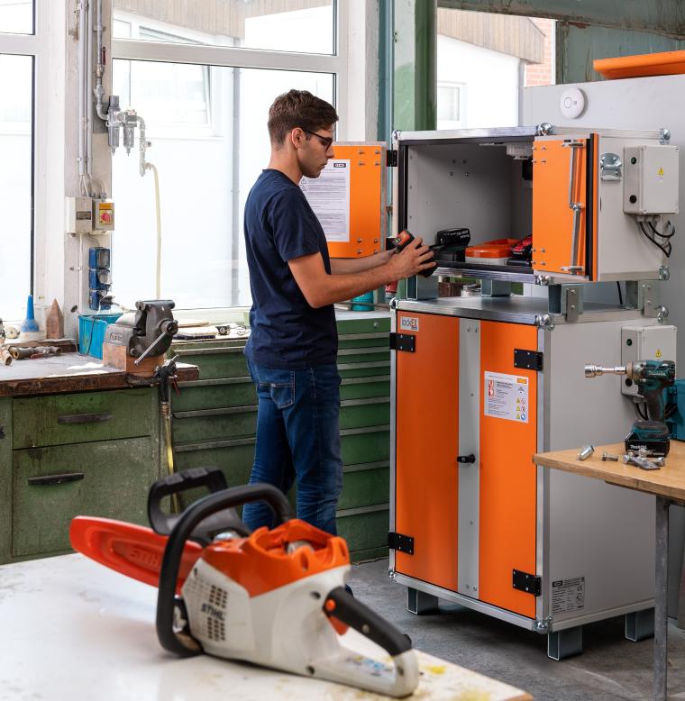 Ein Mann in Arbeitskleidung stellt Lithium Ionen Akkus in einen geöffneten...