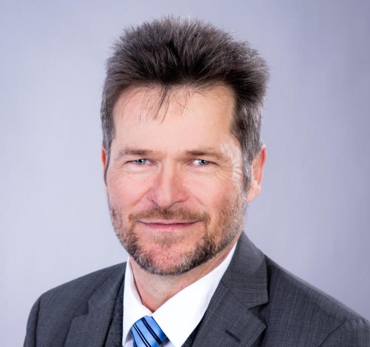 Portrait von Johannes Strümpfel mit Drei-Tage-Bart in weißem Hemd und dunklem...
