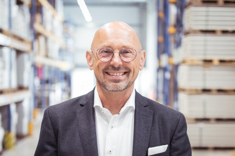 Günther Rossdeutscher in Hemd und Sakko, im Hintergrund ein Lager