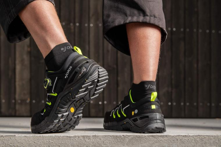 Zwei Beine in schwarzen Socken und robusten, schwarz-neongrünen...