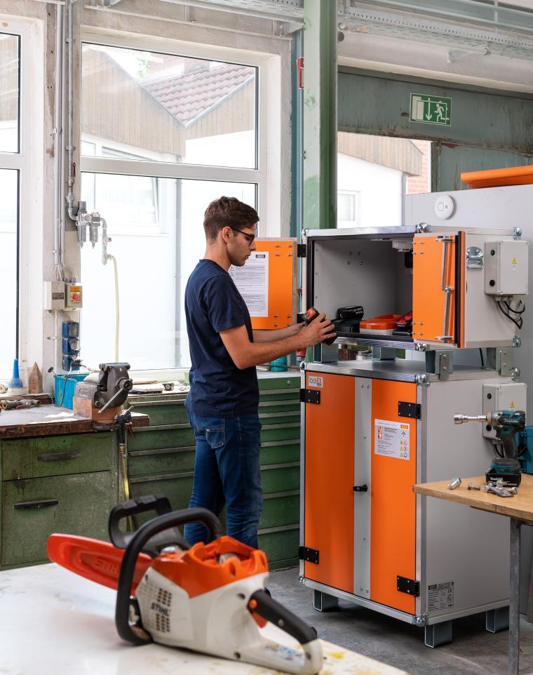 Ein Mann arbeitet in einer Werkstatt an einem großen, orange-weißen Gerät...