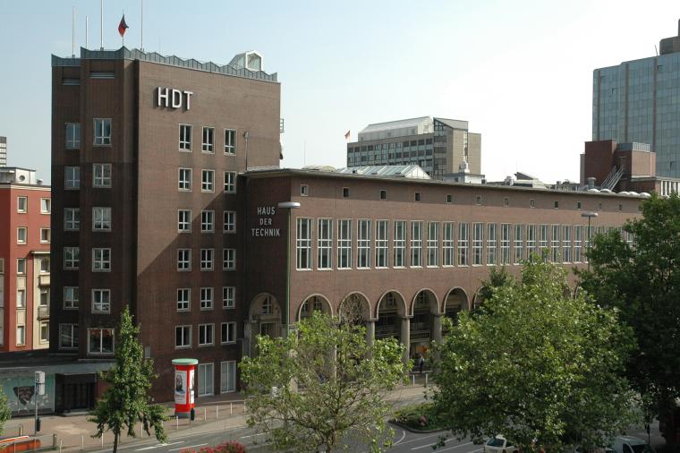 Ein großes Backsteingebäude mit der Aufschrift „HDT – Haus der Technik“...