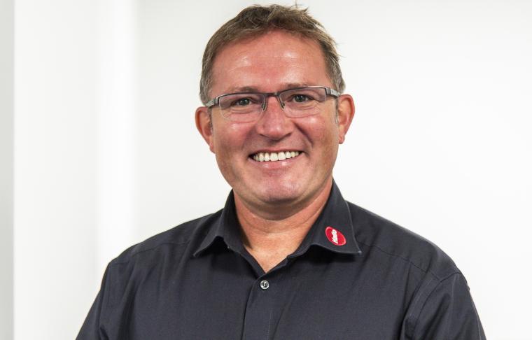 Ein Mann mit Brille in dunklem Hemd mit rotem Hailo Logo am Kragen vor weißem...