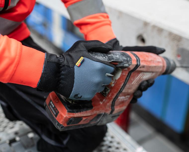 Eine Person trägt Sicherheitshandschuhe und arbeitet mit einem orangefarbenen...