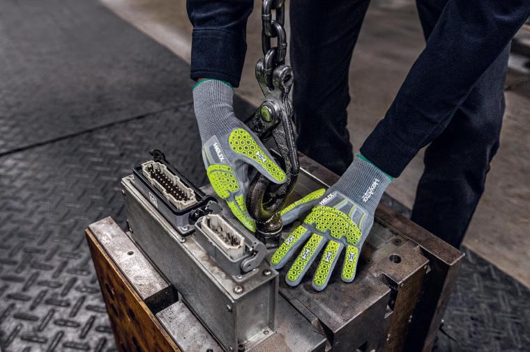 Person mit grau-gelben Schutzhandschuhen hebt mithilfe eines Metallhakens und...