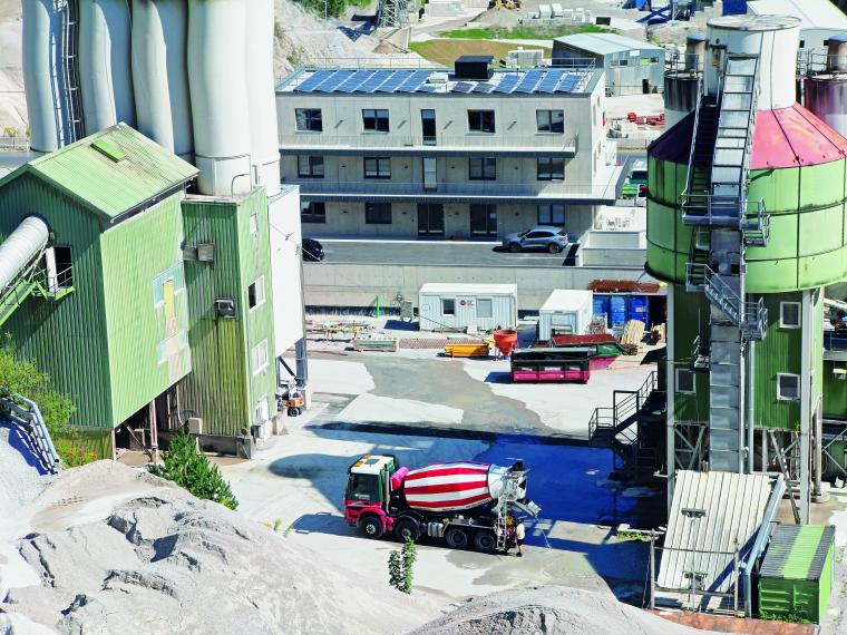 Schotterhalde mit Silos mit Blick auf ein dreistöckiges Bürogebäude mit...