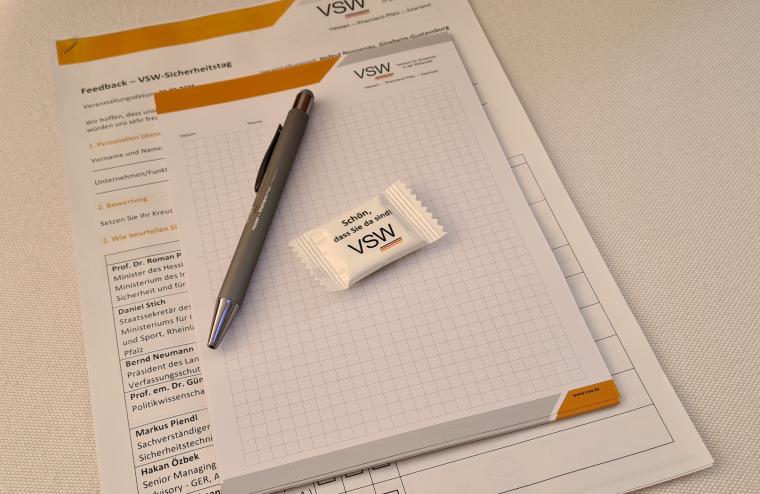 Ein Tisch mit VSW-Dokumenten, einem Kugelschreiber und einer Süßigkeit mit...