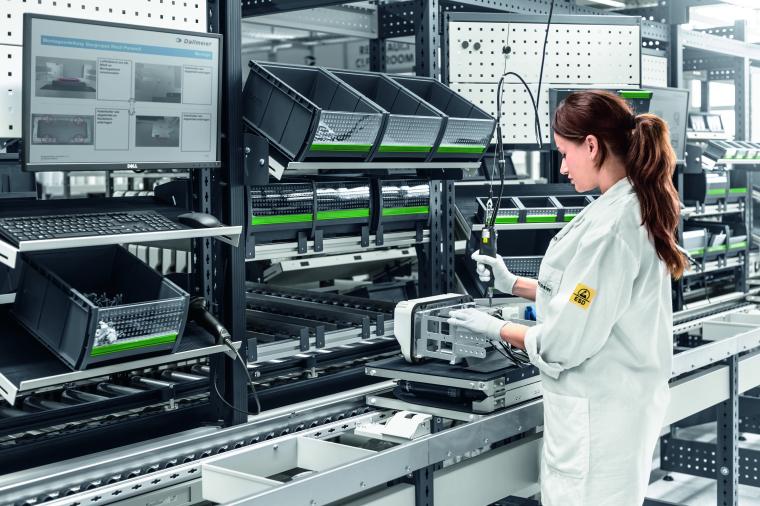 Frau mit Lötapparat mit einem Bauteil auf der Produktionsstraße