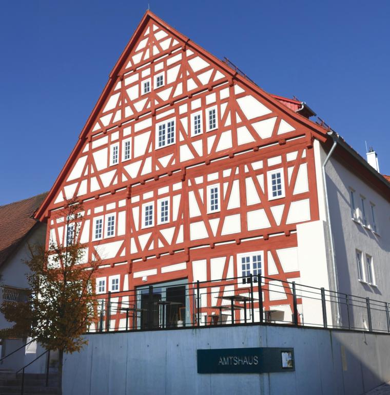 Ein renoviertes Fachwerkhaus mit rotem Fachwerk mit Betonmauer davor