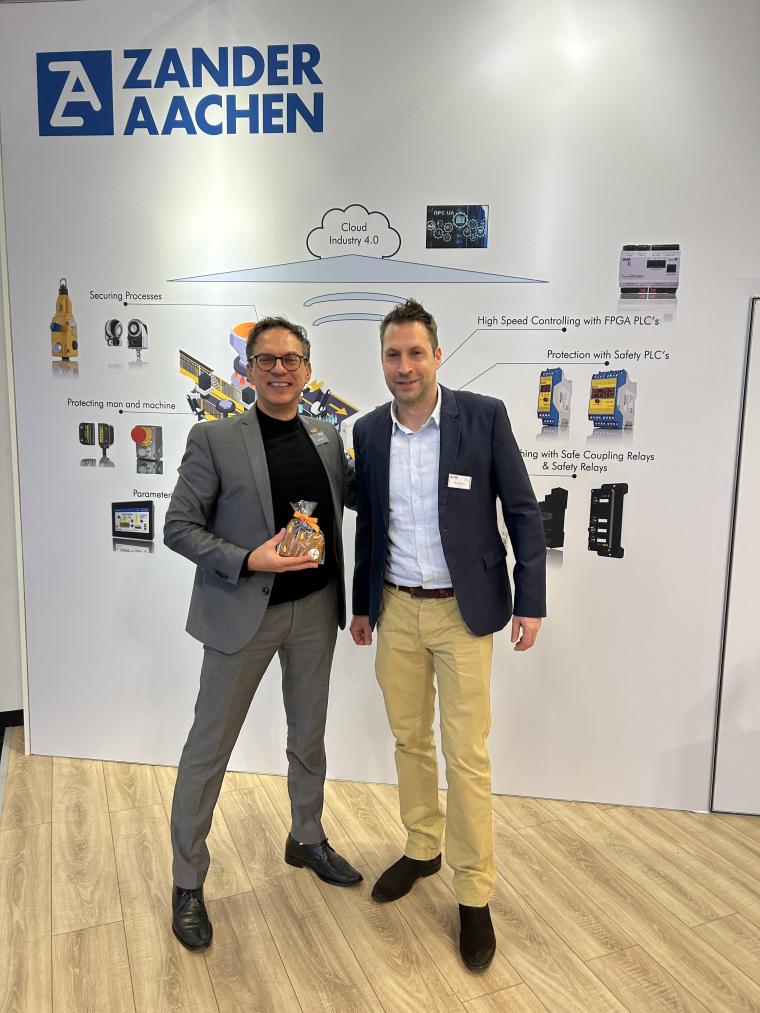 zwei Männer vor einer Messewand