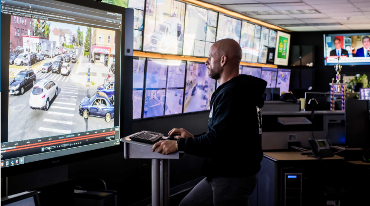 Mann vor Überwachungsvideowand in einer Leitstelle