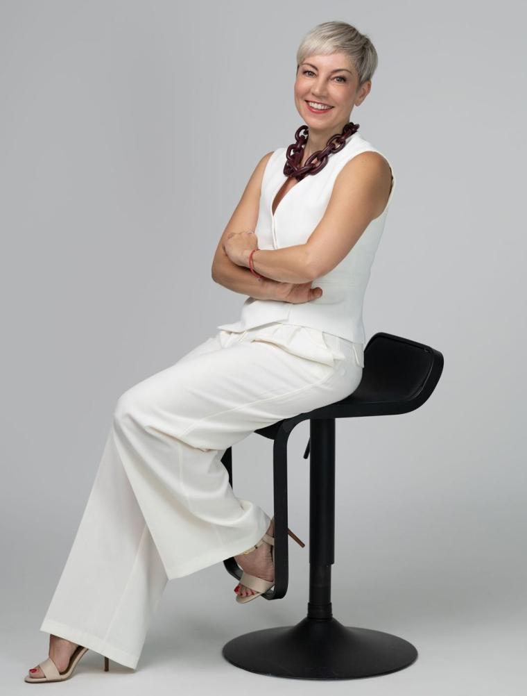 Bild von Lana Djurkin-König im weißen Hosenanzug sitzend auf einem Stuhl