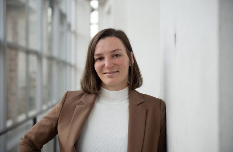 Portrait einer lächelnden Frau mit kinnlangem, braunem Haar, braunem Blazer...