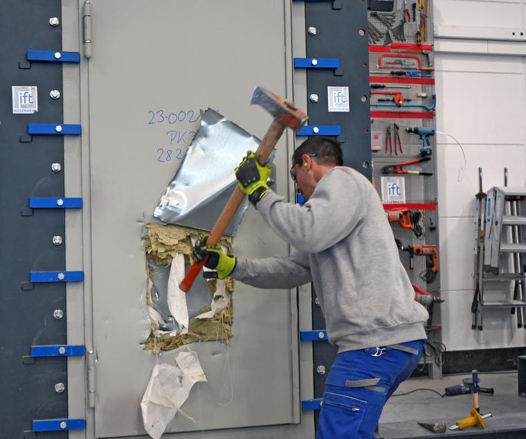 Mann versucht mit einer Axt eine metallbewehrte Tür aufzuhacken