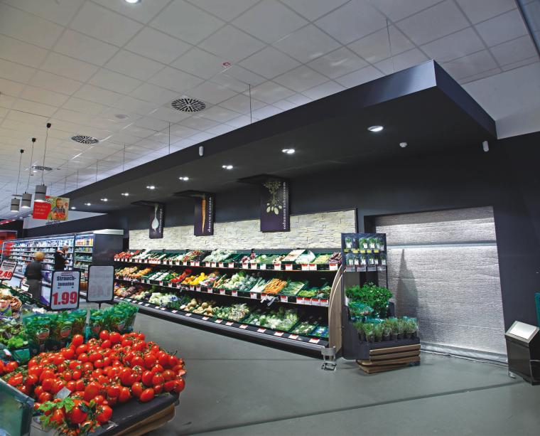 Gemüseabteilung eines Supermarktes. Tomaten und Basilikum im Vordergrund