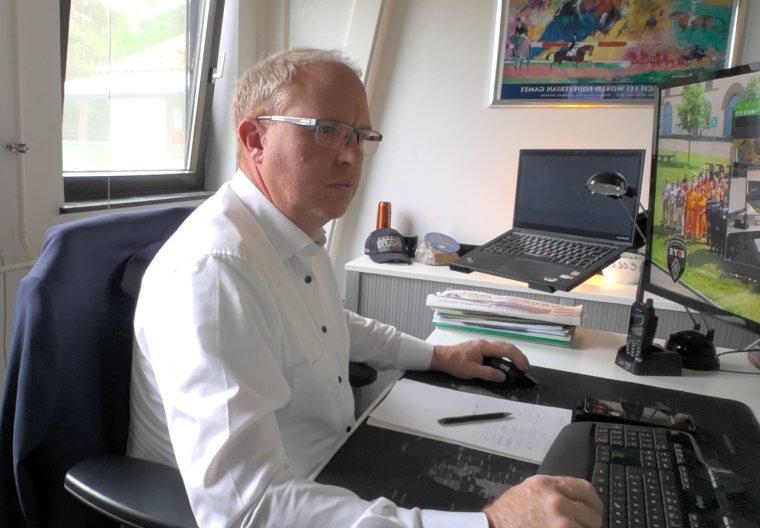 Eine Person sitzt am Schreibtisch in einem Büro, arbeitet am Computer und hat...