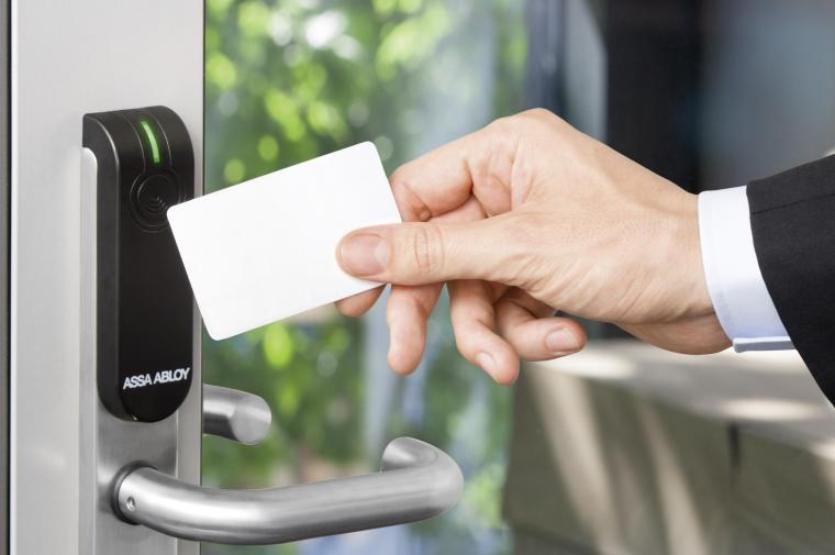 Hand mit Schlüsselkarte an Lesegerät einer Glastür