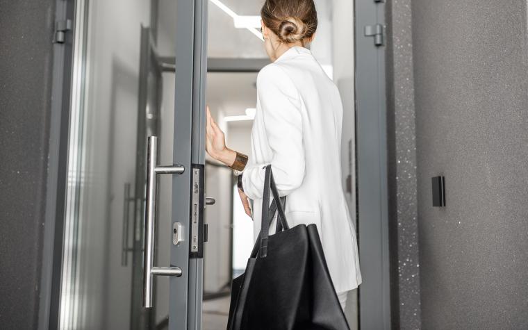 Frau mit Tasche geht durch eine Tür