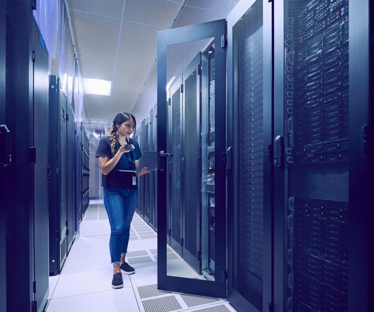 Frau in Serverraum vor geöffneter Tür zu Racks