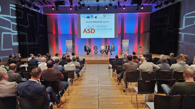 Veranstaltungsraum mit Teilnehmern auf Stühlen mit Podium im Hintergrund