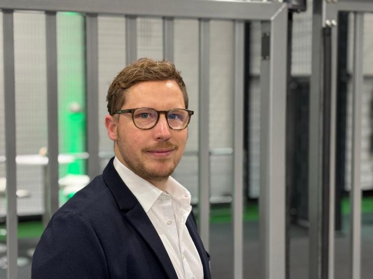 Mann mit schwarzer Brille, Bart, weißem Hemd und dunklem Sakko