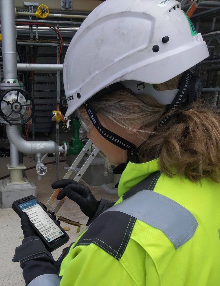 Person in Schutzkleidung und Helm arbeitet auf einem Industriegelände und...
