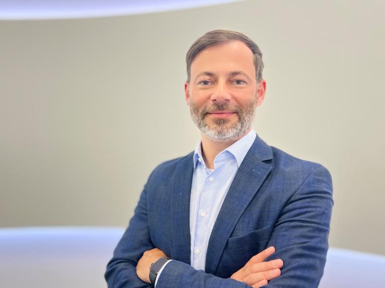 Mann im mittleren Alter und kurzem Bart mit blauem Hemd und dunkelblauem Sakko...