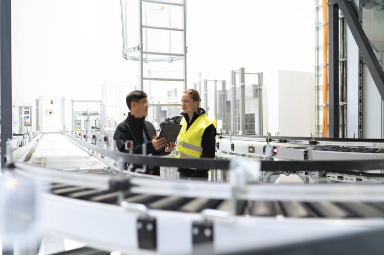 Zwei Personen inspizieren eine industrielle Förderanlage und besprechen Daten...