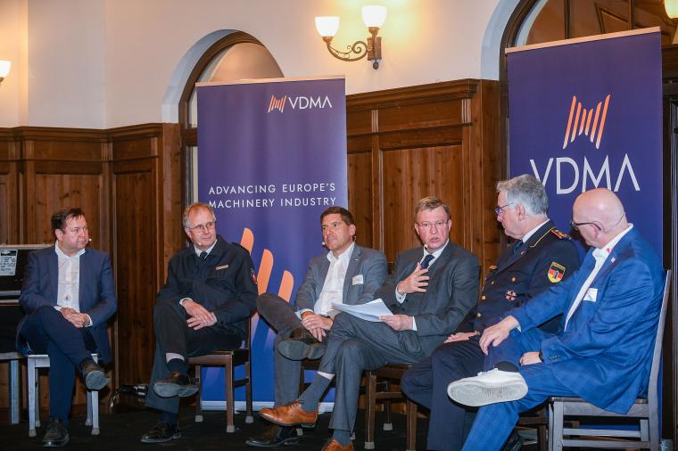Nebeneinander vor Transparenten des VDMA sitzende Diskussionsteilnehmer