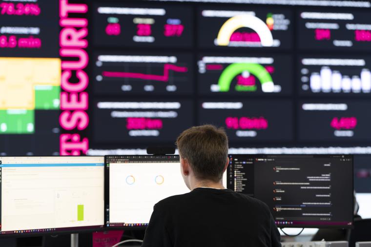 Rückansicht eines jungen Mannes vor verschiedenen Monitoren