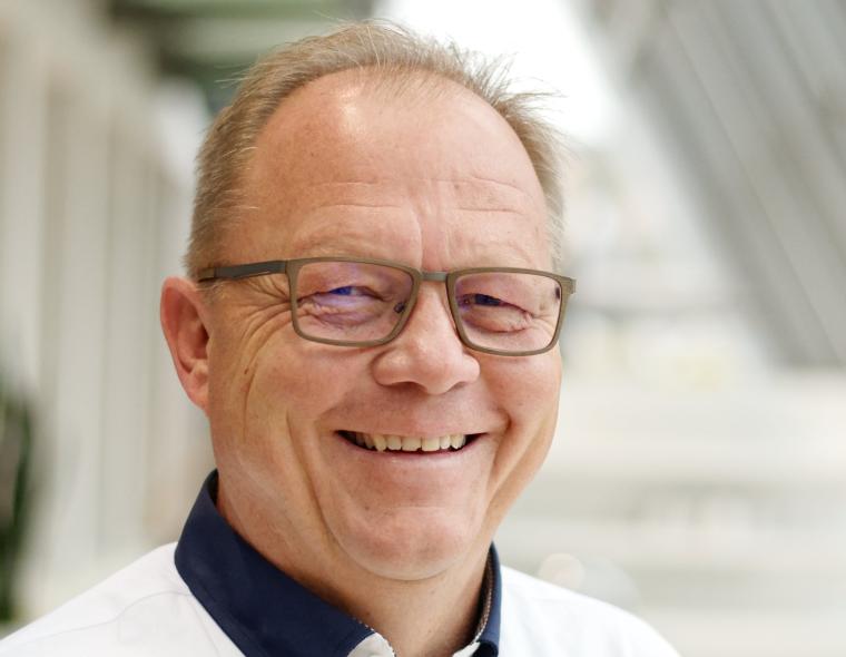 Mann mit heller Brille und weißem Hemd mit blauem Kragen