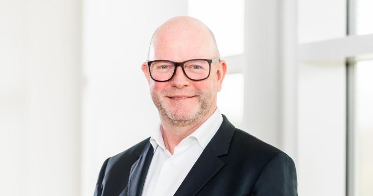 Mittelalter Mann mit Brille, weißem Hemd und dunkler Anzugjacke