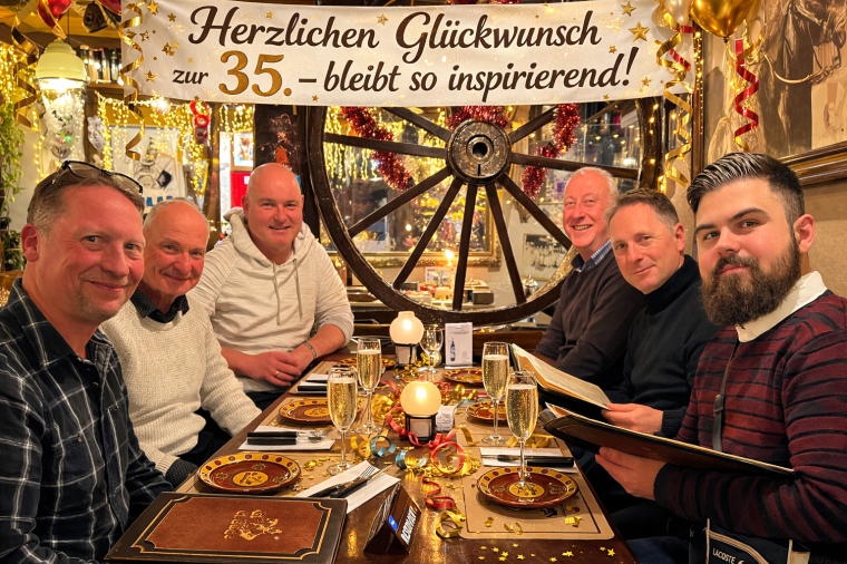 Mehrere Personen sitzen an einem festlich gedeckten Tisch in einem Restaurant;...