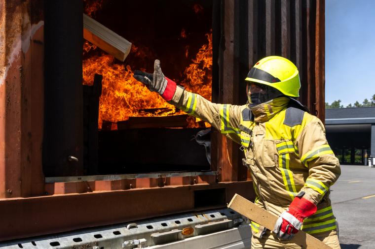 Mann der auf Schild mit Aufschrift „FeuerTrutz 2026“ zeigt, darunter...