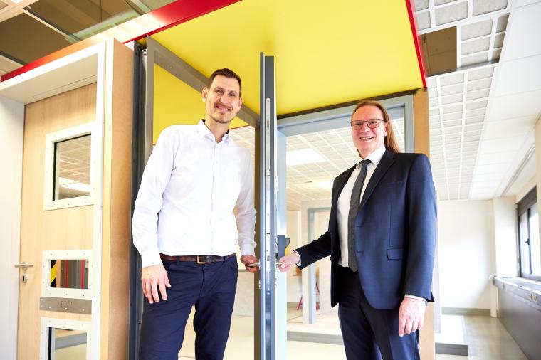 Zwei Männer die jeweils eine Klinke einer geöffneten Tür halten