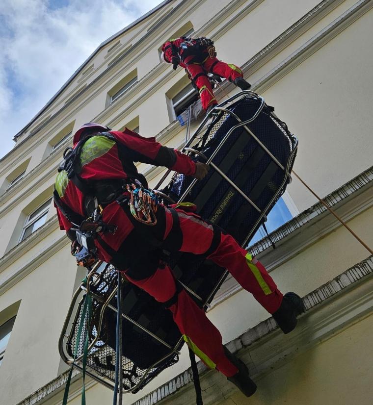 Gesicherte Einsatzkräfte an Fassade mit Trage